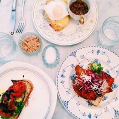 three plates with food on them sitting on a table next to silverware and utensils