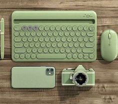 an overhead view of a keyboard, camera and cell phone on a wooden table with other items