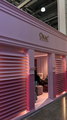 the inside of a store with pink shutters and people sitting on couches in the background