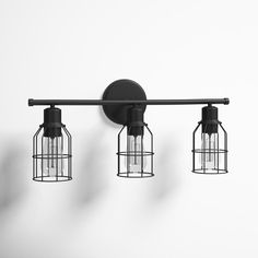 three light fixtures mounted on the wall with caged lights attached to them, one is black