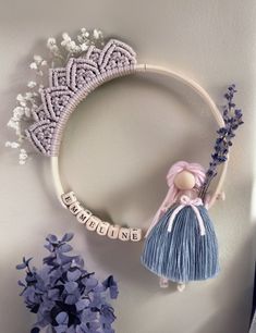 a wreath that has some flowers and a doll hanging on the wall next to it