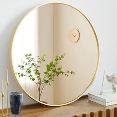 a round mirror sitting on top of a wooden table next to a vase with a plant in it