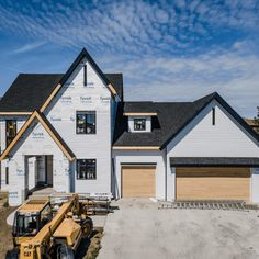 a house under construction with a bulldozer in front of it and a blue sky