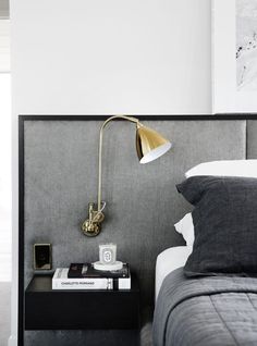 a bed with a gray headboard and two nightstands next to each other in a bedroom