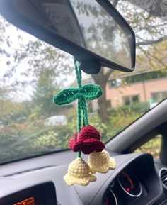 two crocheted bells hanging from the dashboard of a car