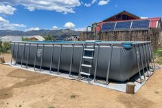 an above ground swimming pool in the middle of a dirt field with mountains in the background