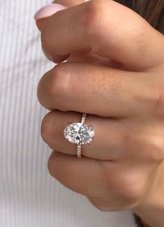 a woman's hand with a diamond ring on her finger and a white shirt