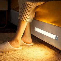 a person's feet are shown under a bed with a light on the side