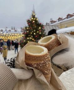 a person holding up some bread in front of a christmas tree with lights on it