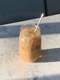 a glass jar filled with liquid sitting on top of a white marble table next to a window