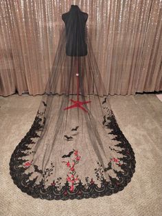 a black and red wedding veil on display in front of a window with curtains behind it