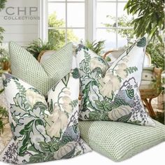 green and white pillows sitting on top of each other in front of a potted plant