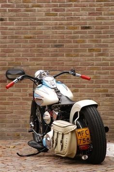 a white motorcycle parked next to a brick wall