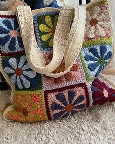 a multicolored crocheted bag sitting on top of a white rug next to a stuffed animal