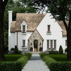 a large white house surrounded by trees and bushes with a stone walkway leading to the front door