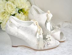 Perfect for Fall/Autumn and Winter Weddings. A Beautiful Satin Bridal Shoes, with an elegant lace overlay. A comfortable 7.5cm wedge heel offers the perfect amount of height and stability. Finished with a pearlescent floral shoe clip with crystals for a subtly amount of shine.  Design Details: * Handmade  * Made with Extra Padded Soles for Comfort * Heel Height: 7.5cm  * Colour Availability: Ivory or White * Peep Toe * Wedge Heel * Lace Finish  * Removable Shoe Clip Included with your order: * H Bridal Wedges, Lace Bridal Shoes, Wedge Wedding Shoes, Lace Wedges, Heel Protector, Wedding Shoes Lace, Winter Weddings, Floral Shoes, Womens Wedding Shoes