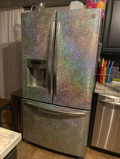 a metallic refrigerator with hologish on the door and ice maker next to it