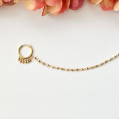 a close up of a chain with a ring on it and flowers in the background