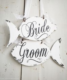 two wooden signs with the words bride and groom hanging from hooks on a white wall