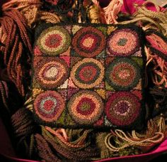 a crocheted square is sitting on top of some yarn and other items in a pink bag