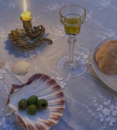 an empty shell and some olives on a table with a candle in the middle