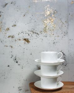 three white cups stacked on top of each other in front of a wall with moldy paint