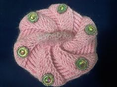 a pink knitted hat with green buttons