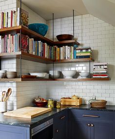 a kitchen with blue cabinets and shelves filled with cookbooks, bowls and utensils