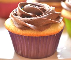 cupcakes with chocolate frosting and sprinkles sitting on a table