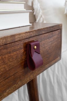 a close up of a drawer on a bed with books and pillows in the background