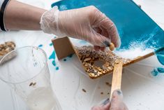 a person in gloves and latex gloves is decorating a birdhouse with blue paint