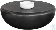 a white bowl sitting on top of a black ottoman that is shaped like a stool