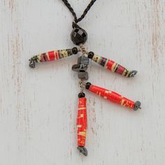 a multicolored beaded necklace hanging from a cord on a white wooden surface