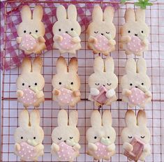 some bunny cookies on a wire rack with pink and white polka dot ribbon around them