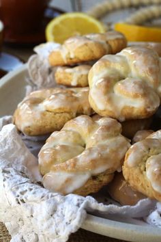 glazed donuts with icing on a plate next to lemon wedges and tea