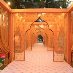 an orange and white wedding setup with draping, flowers and greenery on the floor