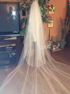 a wedding veil hanging from the ceiling in front of a flat screen tv with greenery on it