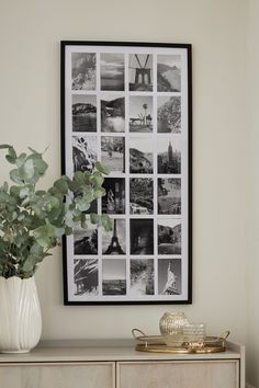 a white vase with some flowers on top of a wooden dresser next to a black and white photo