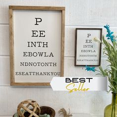 an eye chart is hanging on the wall next to a vase with flowers