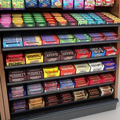 a display case filled with lots of different flavored candy bars and boxes on top of each shelf