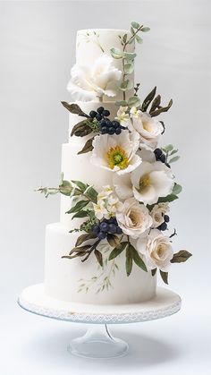 a three tiered wedding cake with white flowers and greenery