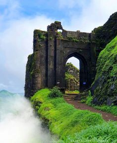 an arch in the side of a mountain with grass growing on it's sides