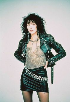 a woman with black hair wearing a leather jacket and skirt