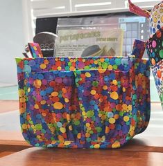 two colorful bags sitting on top of a wooden table