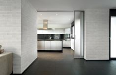 an open kitchen and living room area in a modern style house with white walls, black flooring and large glass doors