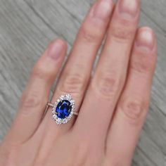 a woman's hand with a blue and white diamond ring on top of it