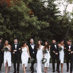 a group of people standing next to each other in front of some trees and bushes