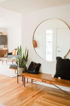 a living room with wooden floors and a large round mirror on the wall above it