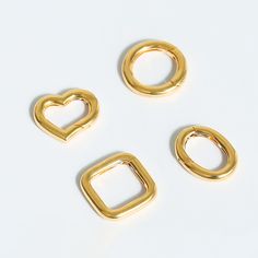 three pieces of gold colored metal on a white surface with the shape of a heart