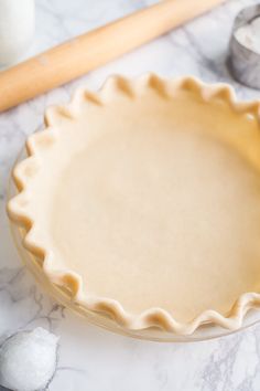 an uncooked pie crust sitting on top of a table next to a rolling pin